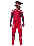 Alpinestars 2025 Fluid Haul Gearset, motorcross outfit in felrood en zwart, rood jersey met zwarte mouwen en witte logo's, bijpassende rode broek met witte sterlogo's, zwarte helm met goudgetinte bril en rode laarzen, complete uitrusting voor off-road rijden
