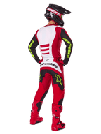 Alpinestars 2025 Fluid Haul Gear Set, motorcrosser van achteren gezien, helderrood en zwart met witte panelen, neongele branding op mouwen en broek, bijpassende rode laarzen en zwarte helm, complete professionele off-road race-uitrusting