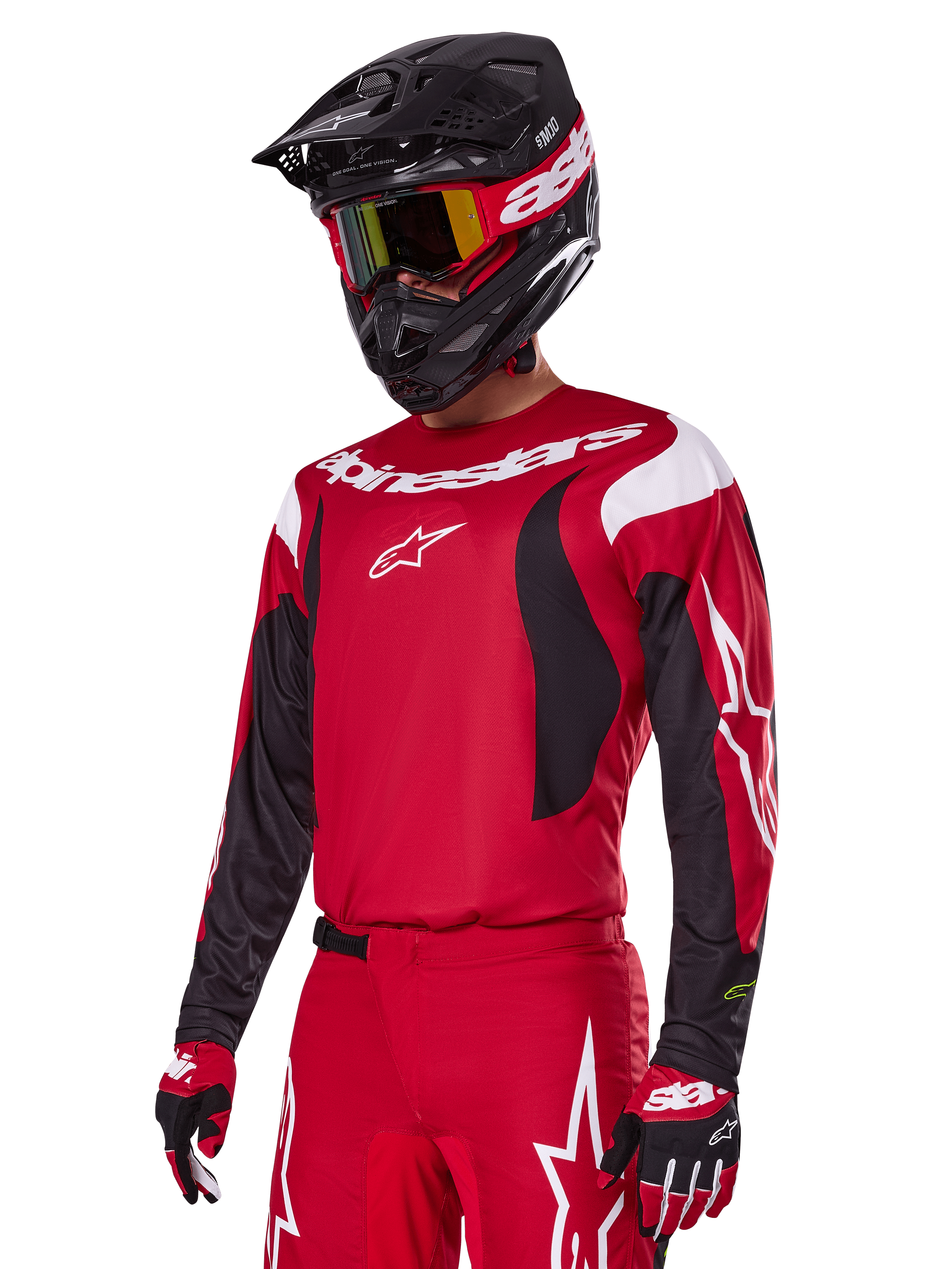 Alpinestars 2025 Fluid Haul Gear Set in het rood, motorcrossrijder in rode jersey met witte en zwarte accenten, bijpassende rode broek met witte graphics, zwarte helm met witte branding, rood-gele crossbril en rood-zwarte handschoenen, gecoördineerde motorcross race-outfit