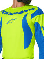 Alpinestars 2025 Fluid Haul Jersey, motocross shirt, fluorgeel en blauw, met opvallende blauwe Alpinestars-branding op de borst en golvende blauwe patronen op de schouders, sportieve pasvorm voor off-road racen