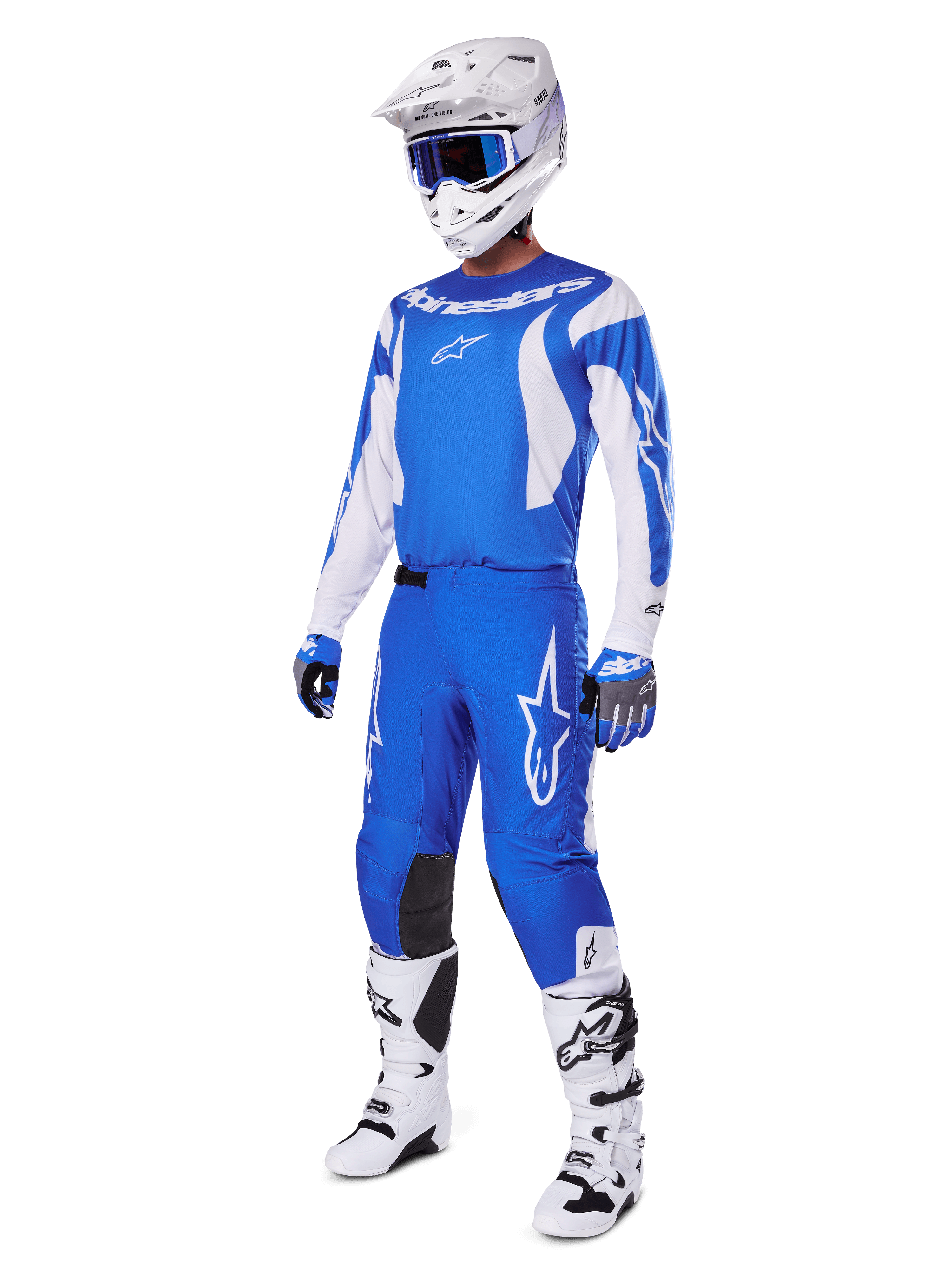 Motorcrosser die de volledige 2025 Fluid Haul Gear Set draagt, blauwe en witte jersey en broek met Alpinestars-branding, witte helm met blauwe bril, witte laarzen en blauwe handschoenen, gecoördineerde race-outfit voor off-road motorcross.