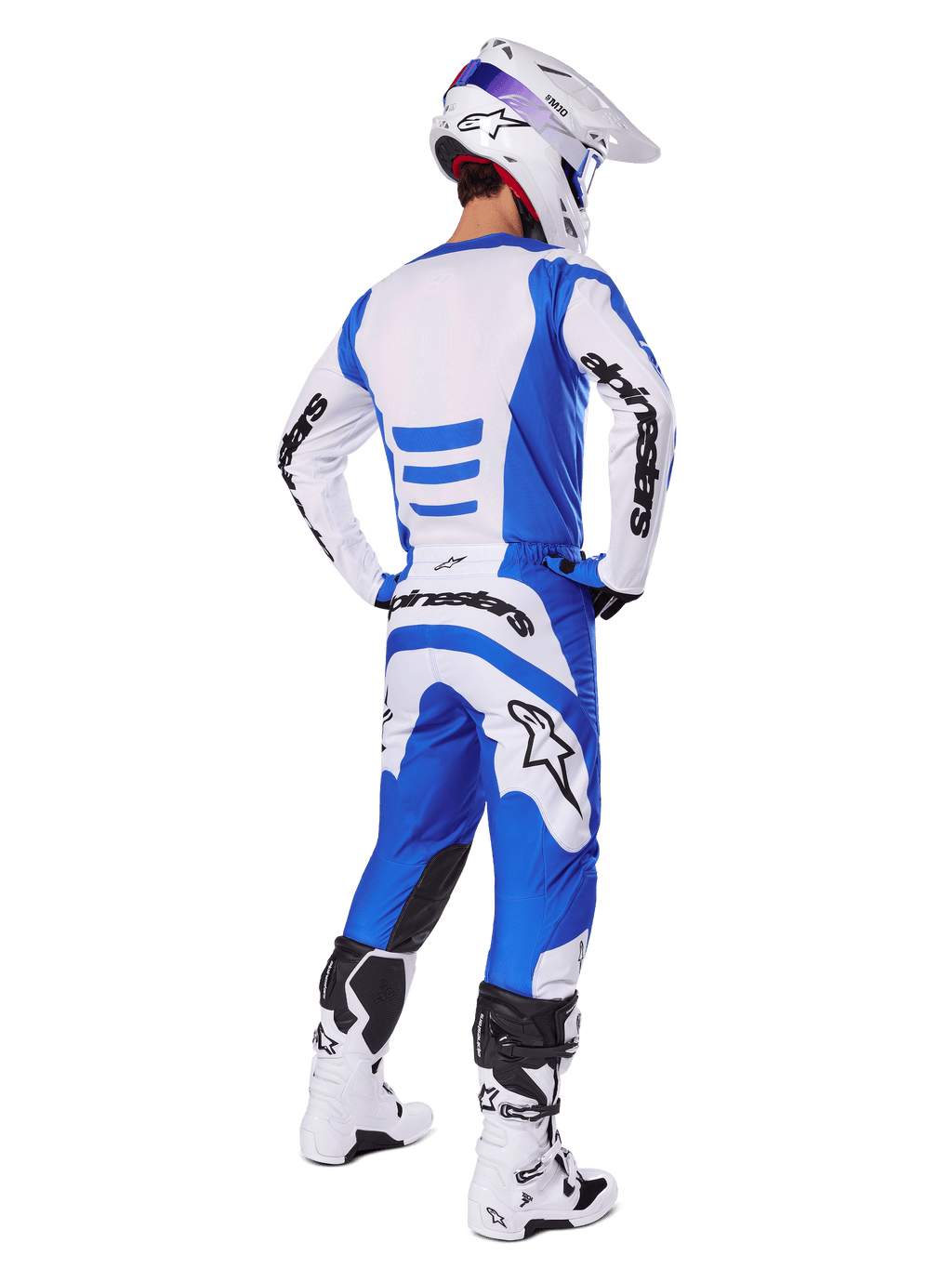 Motorcrosser vanaf de achterkant in de Alpinestars 2025 Fluid Haul Gear Set, blauw-wit jersey met bijpassende broek, witte helm met blauwe accenten en wit-zwarte racelaarzen, gecoördineerde off-road race-outfit