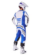 Motorcrosser vanaf de achterkant in de Alpinestars 2025 Fluid Haul Gear Set, blauw-wit jersey met bijpassende broek, witte helm met blauwe accenten en wit-zwarte racelaarzen, gecoördineerde off-road race-outfit