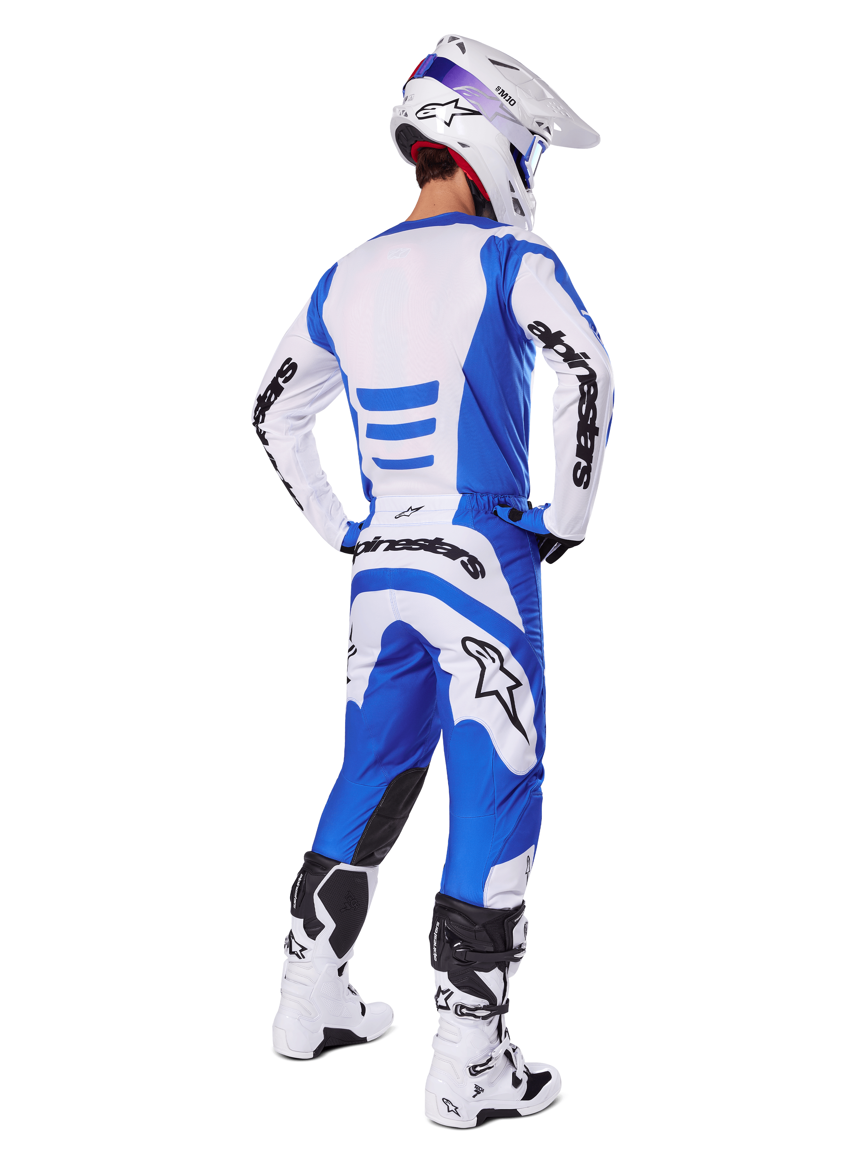 Motorcrosser vanaf de achterkant in de Alpinestars 2025 Fluid Haul Gear Set, blauw-wit jersey met bijpassende broek, witte helm met blauwe accenten en wit-zwarte racelaarzen, gecoördineerde off-road race-outfit