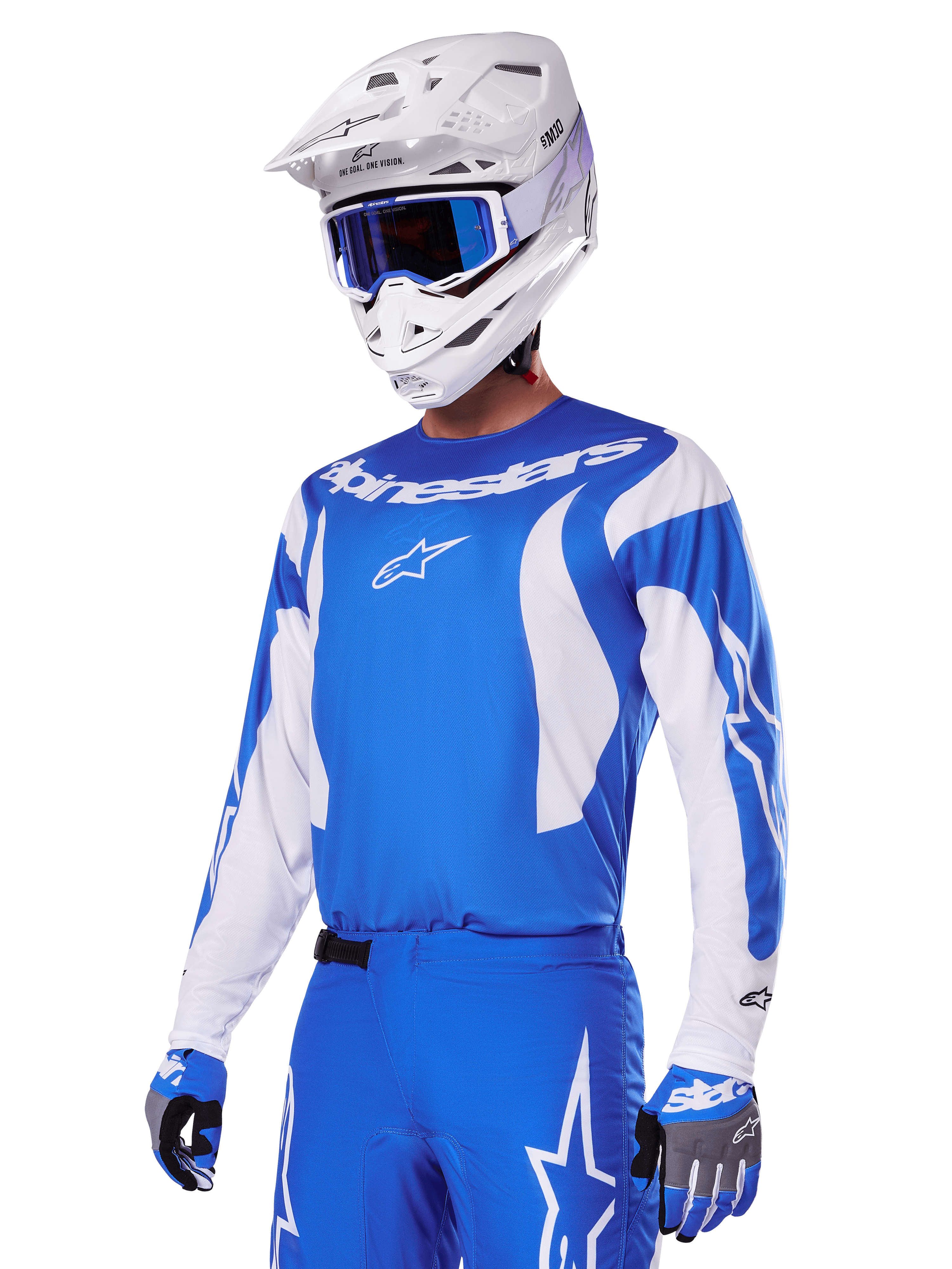 Motorcrosser draagt de Alpinestars 2025 Fluid Haul Gear Set in blauw en wit, met een blauwe jersey met witte accenten, bijpassende blauwe broek met sterlogo's, een witte helm met blauwe bril en gecoördineerde blauwe en grijze handschoenen, complete off-road race-outfit.