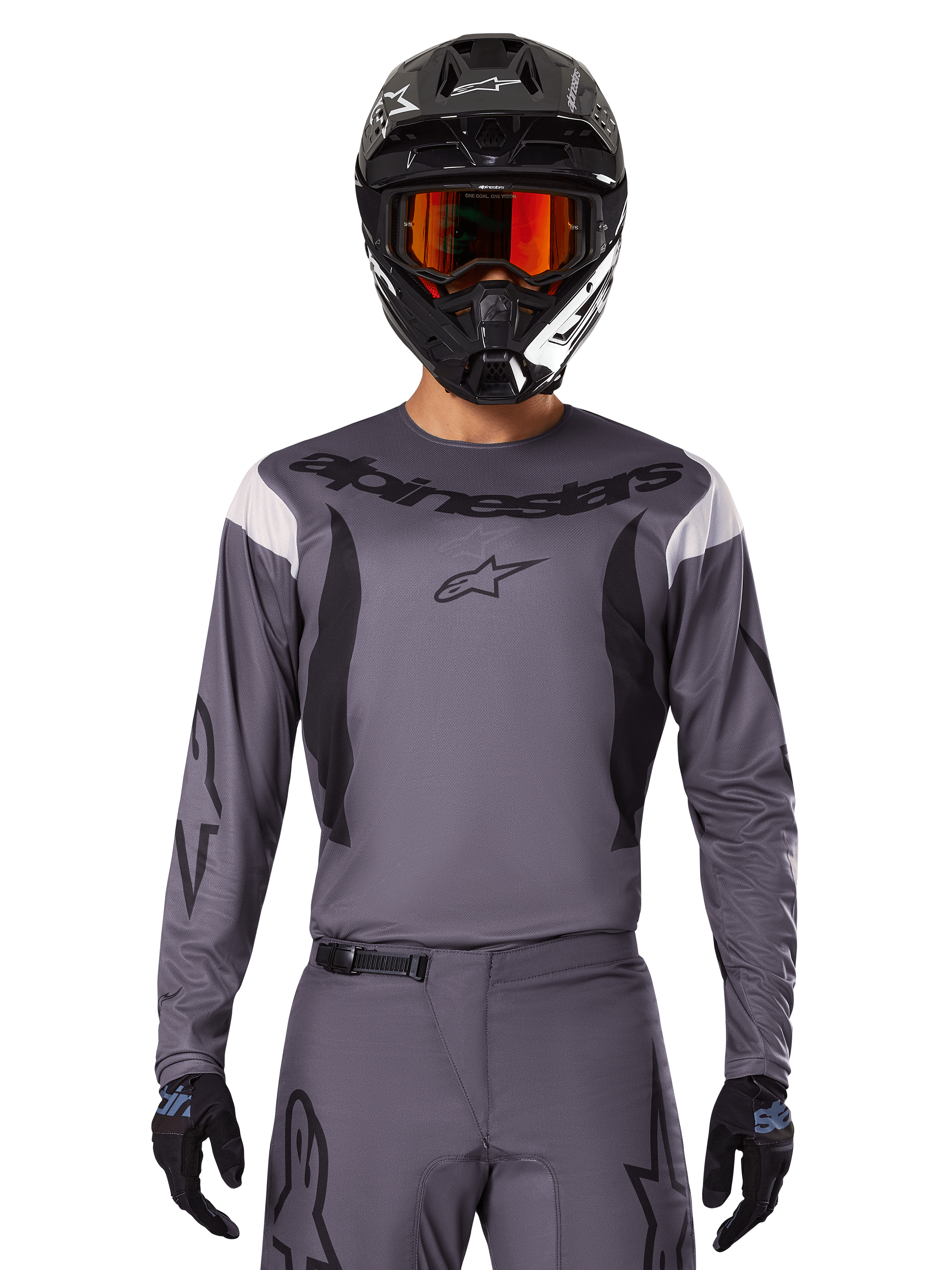 Alpinestars 2025 Fluid Haul Jersey en Gear Set, motorcross outfit, grijs met zwarte en witte accenten, lange mouwen en opvallende branding, zwarte helm met oranje bril en zwarte handschoenen, compleet tenue voor off-road racen