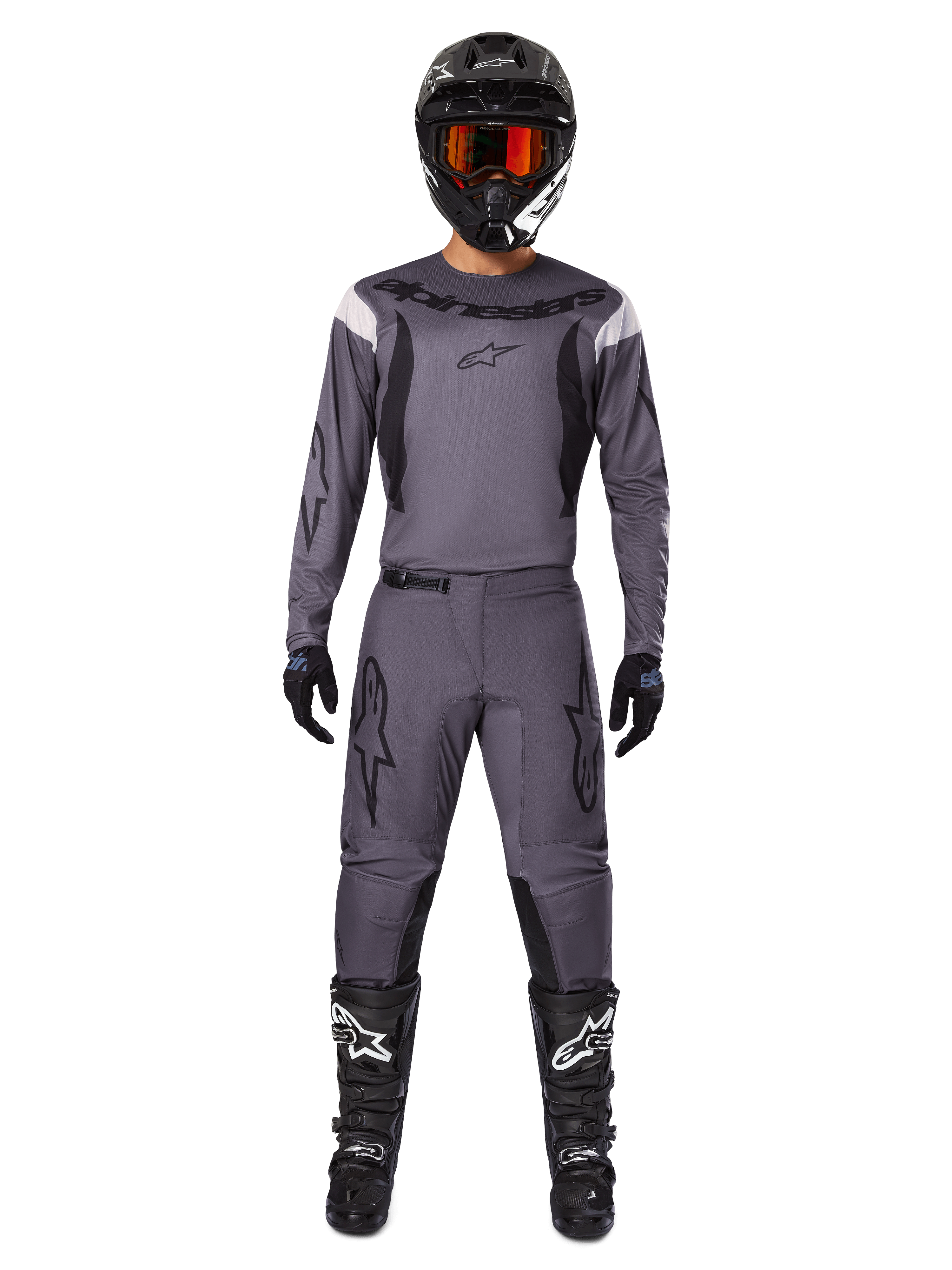 Alpinestars 2025 Fluid Haul Gear Set, motorcross uitrusting, grijs, grijze jersey en broek met zwarte accenten, zwarte helm met oranje bril, zwarte laarzen met witte logo's, gecoördineerde race-outfit voor off-road prestaties