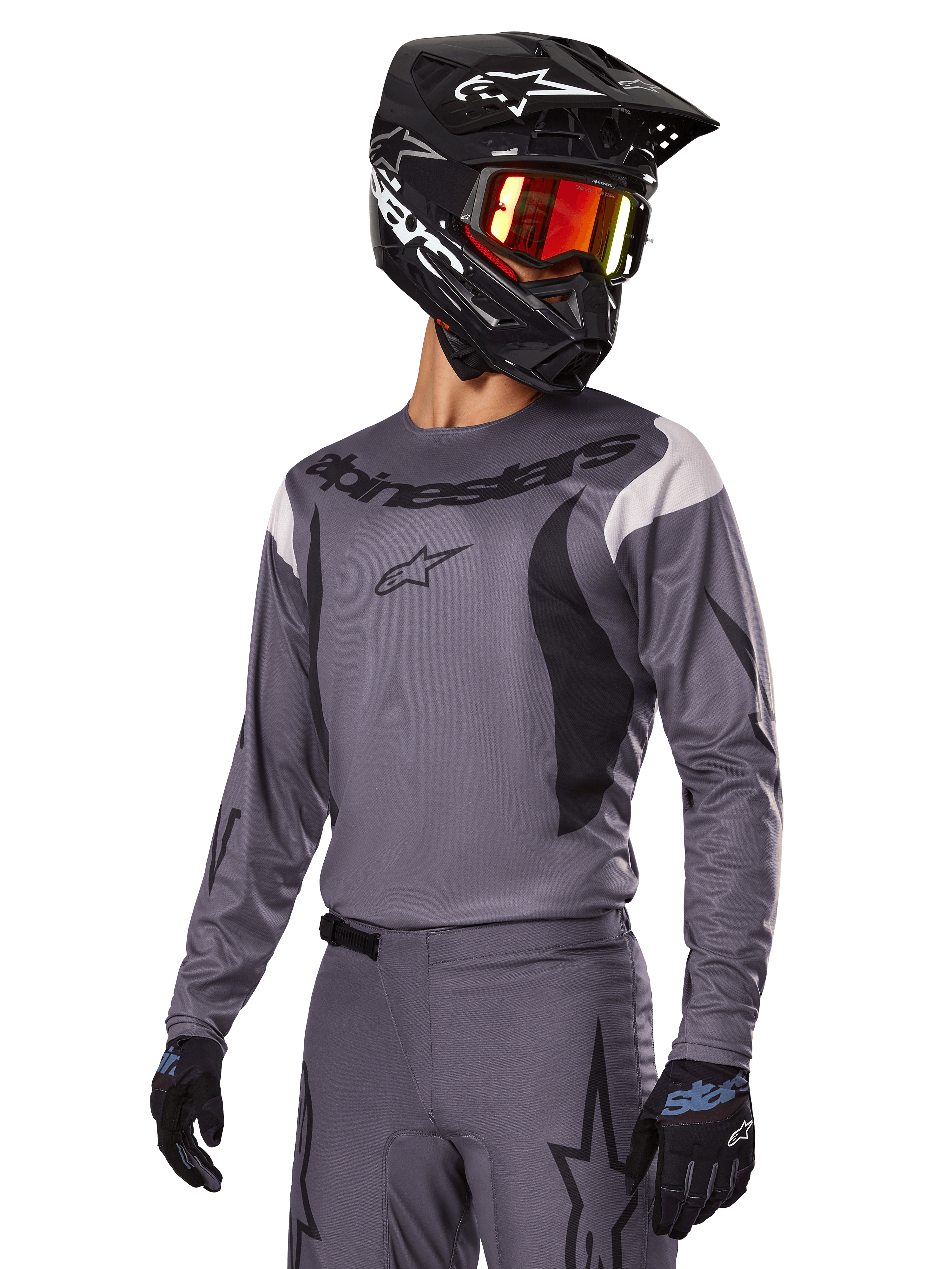 Alpinestars 2025 Fluid Haul Gear Set, grijs motorcross shirt en broek met zwarte en witte accenten, gedragen met een zwarte helm, rode crossbril en zwarte handschoenen, sportieve pasvorm voor off-road rijden