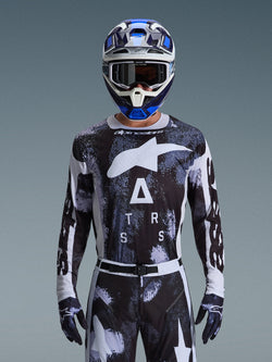 Alpinestars 2026 Racer Lahnd Jersey, motorcross shirt, Iron Camo-patroon in zwart en wit, met een opvallend Star-logo en ASTARS-belettering, gedragen met bijpassende broek en een blauwe motorcrosshelm