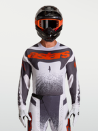 Alpinestars Techstar Swan jersey, heren motorcrossjersey in wit en grijs met rood fluo accenten, atletische racepasvorm, gedragen door model.