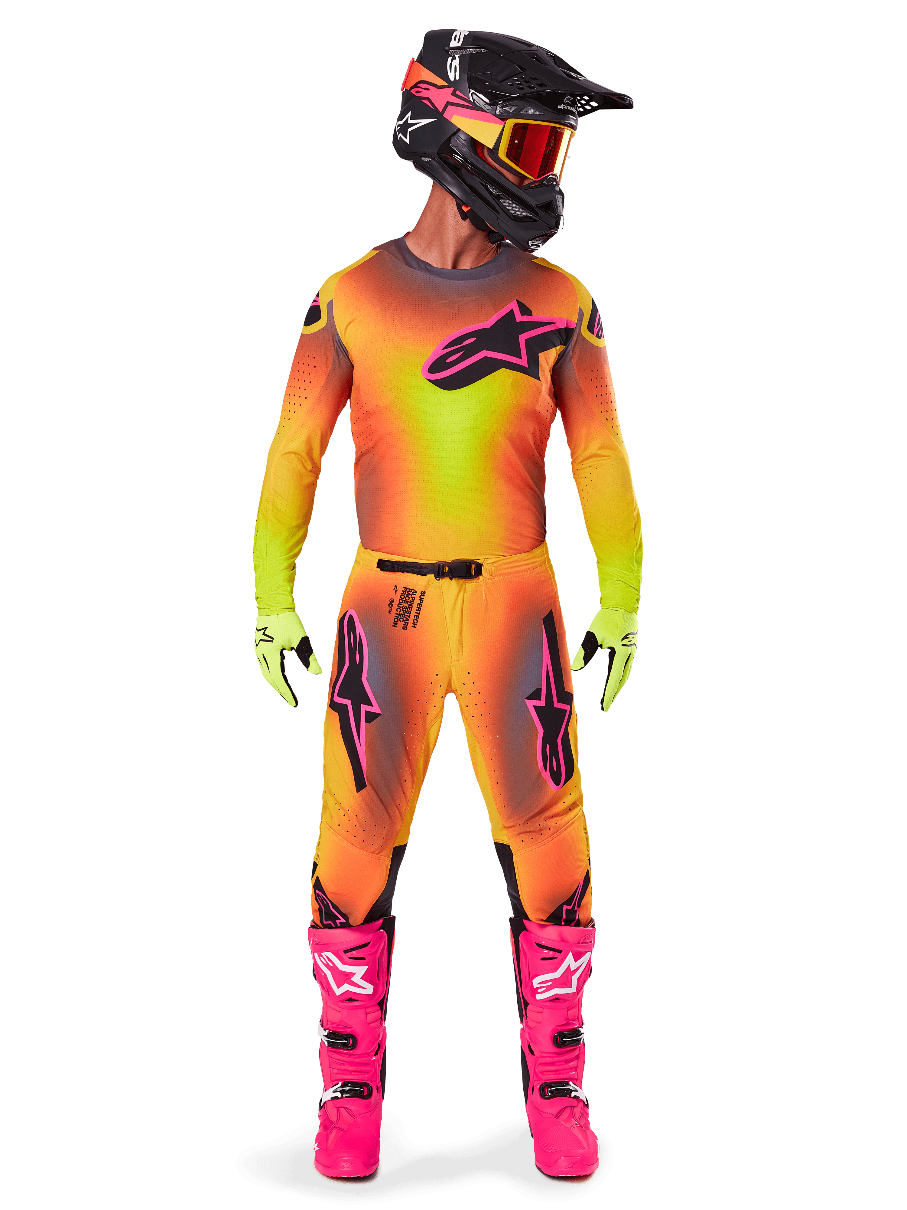 Motorcrossrijder in volledige race-uitrusting, 2025 Supertech Lipan Jersey en broek in een geel-oranje kleurverloop met roze accenten, zwarte helm met bijpassende roze graphics, felroze laarzen en limoengroene handschoenen, gecoördineerde Alpinestars off-road outfit.