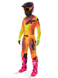 Motorcrossrijder in de 2025 Alpinestars Supertech Lipan gearset, jersey en broek met geel en oranje kleurverloop en roze accenten, zwarte helm met geel-rode crossbril, felgele handschoenen en felroze laarzen, gecoördineerde off-road race-outfit