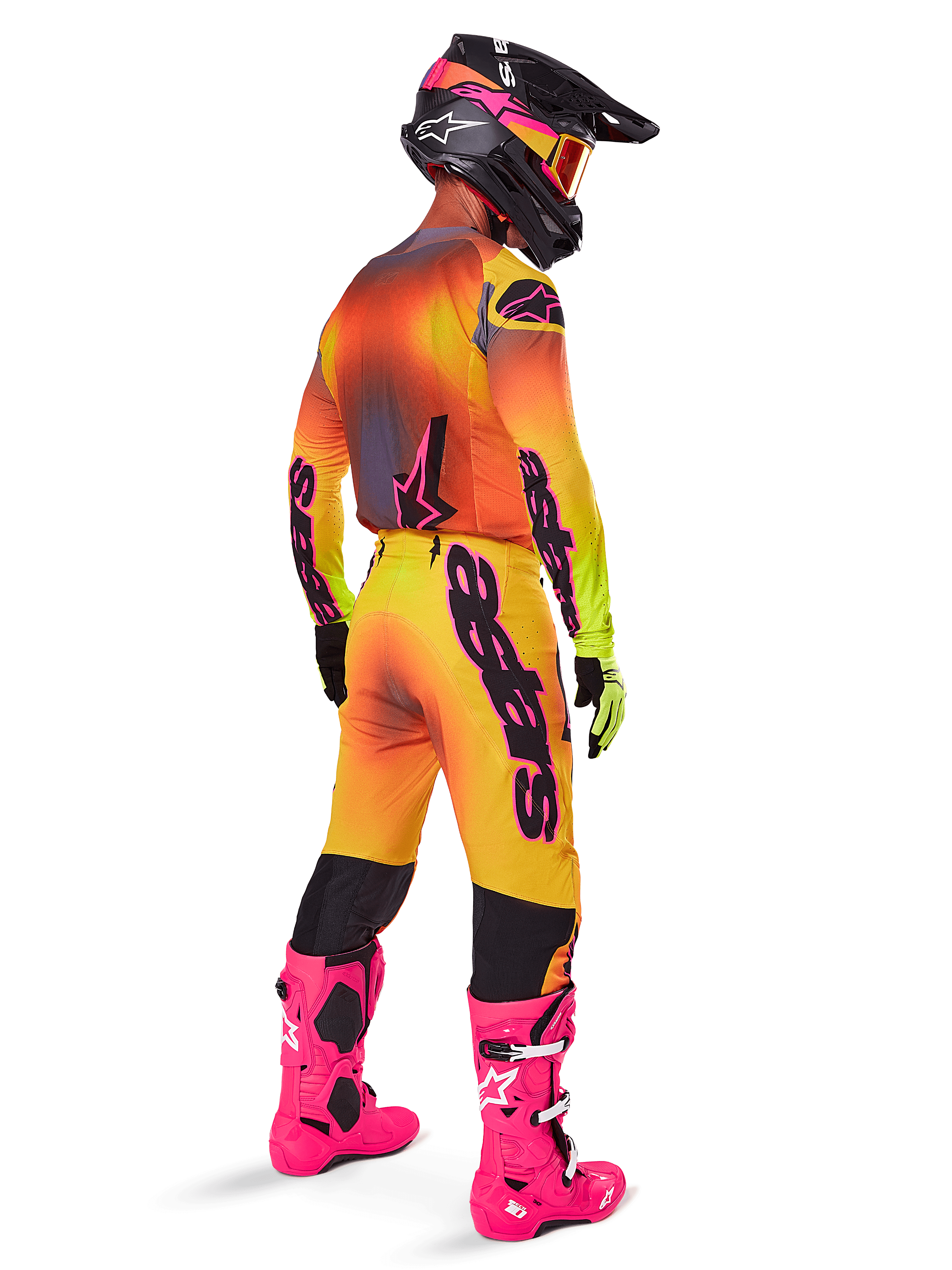 Alpinestars 2025 Supertech Lipan Gear Set, motorcrosser van achteren gezien, geel en oranje jersey met kleurverloop en roze accenten, bijpassende broek, felroze laarzen en zwarte helm met roze en gele graphics, professionele race-outfit