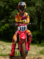 Motorcrossrijder op een rode Honda crossmotor met startnummer 18, draagt Alpinestars 2025 Supertech Lipan Jersey en bijpassende broek in geel en roze, felroze Alpinestars laarzen, Red Bull helm, professionele race-uitrusting voor off-road prestaties