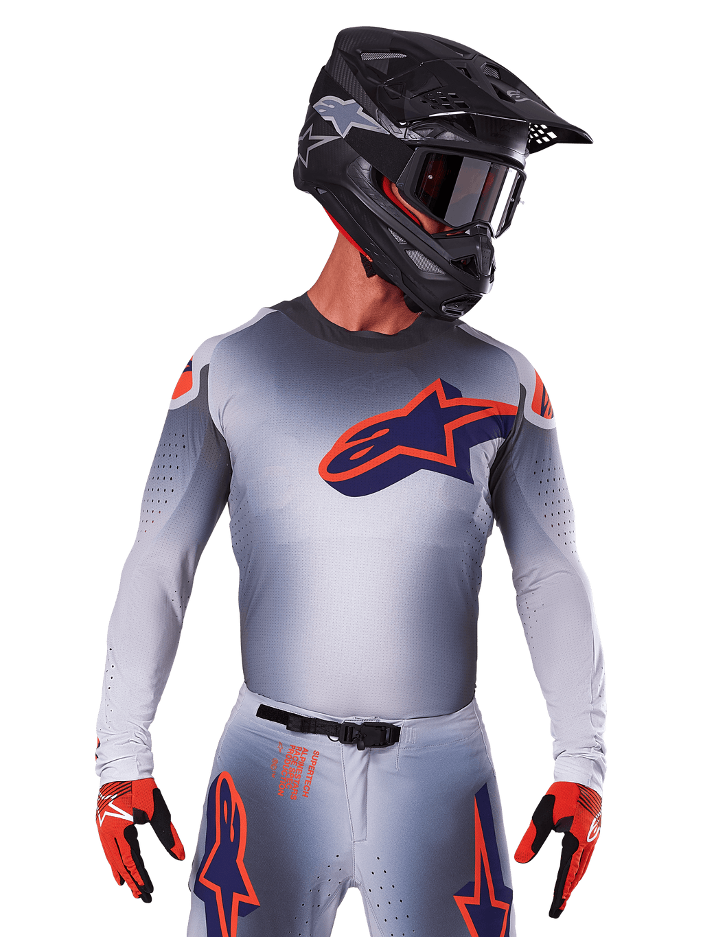 Alpinestars 2025 Supertech Lipan Jersey, motorcross shirt, grijs met oranje en navy blauwe accenten, performance top met lange mouwen en geperforeerde ventilatie, gedragen met zwarte helm en rode handschoenen, strak racing design