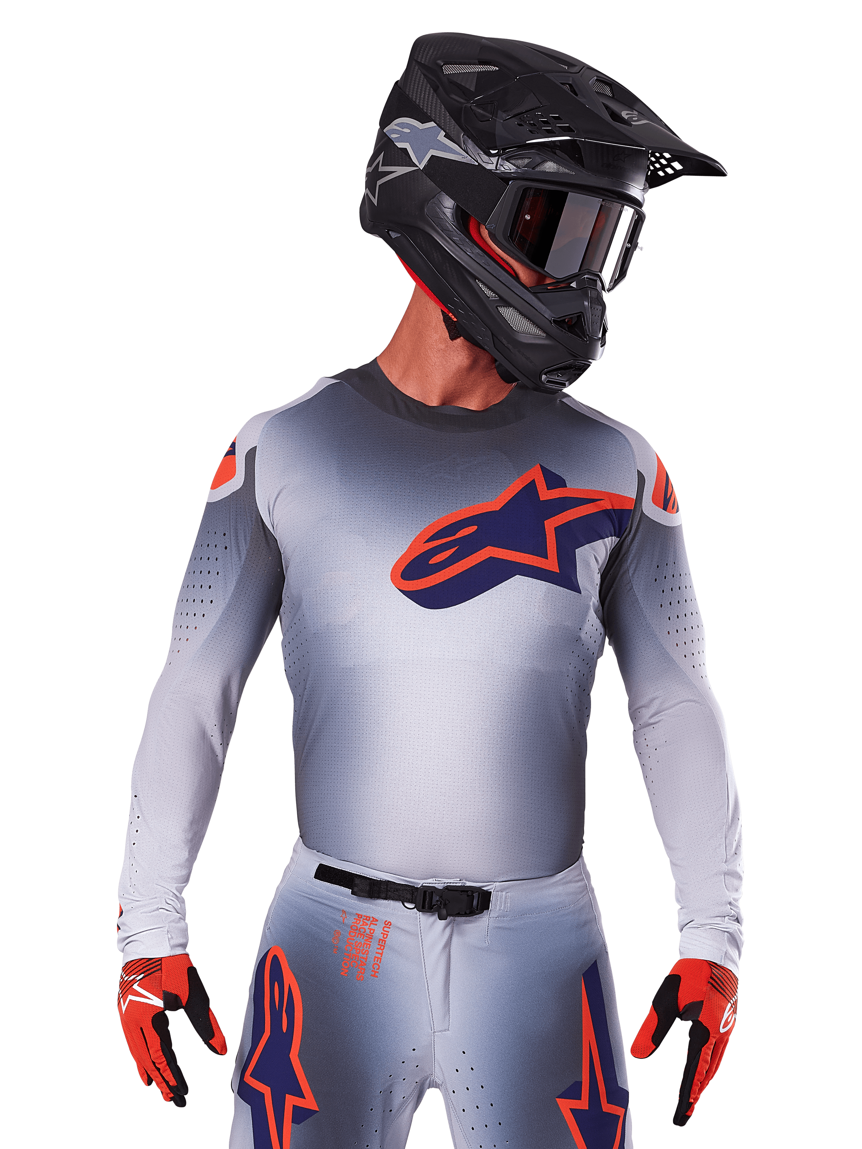 Alpinestars 2025 Supertech Lipan Jersey, motorcross shirt, grijs met oranje en navy blauwe accenten, performance top met lange mouwen en geperforeerde ventilatie, gedragen met zwarte helm en rode handschoenen, strak racing design