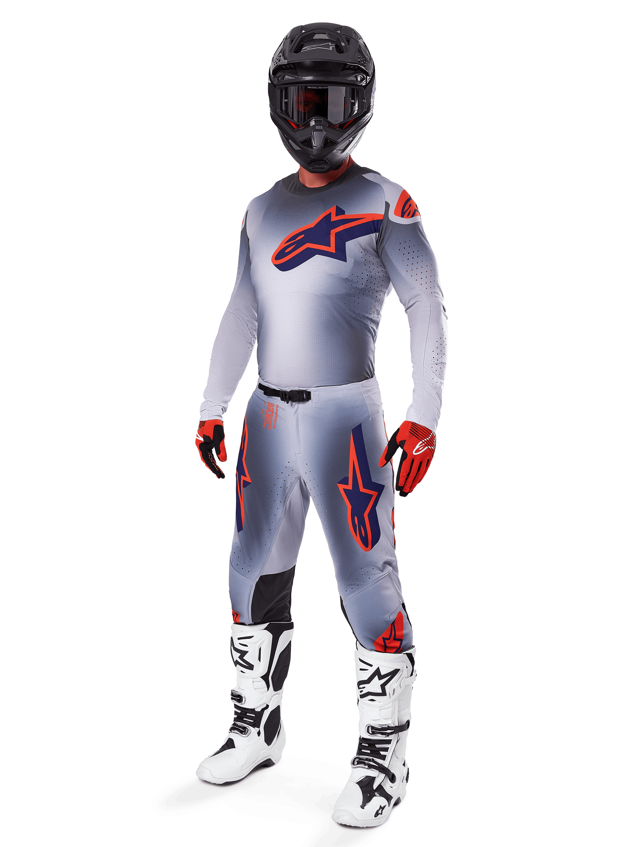 Motorcrosser die de Alpinestars 2025 Supertech Lipan Jersey draagt in grijs en oranje fluo, bijpassende grijze broek met oranje accenten, zwarte helm, witte en zwarte laarzen en oranje-zwarte handschoenen, professionele uitrustingset voor off-road racing.