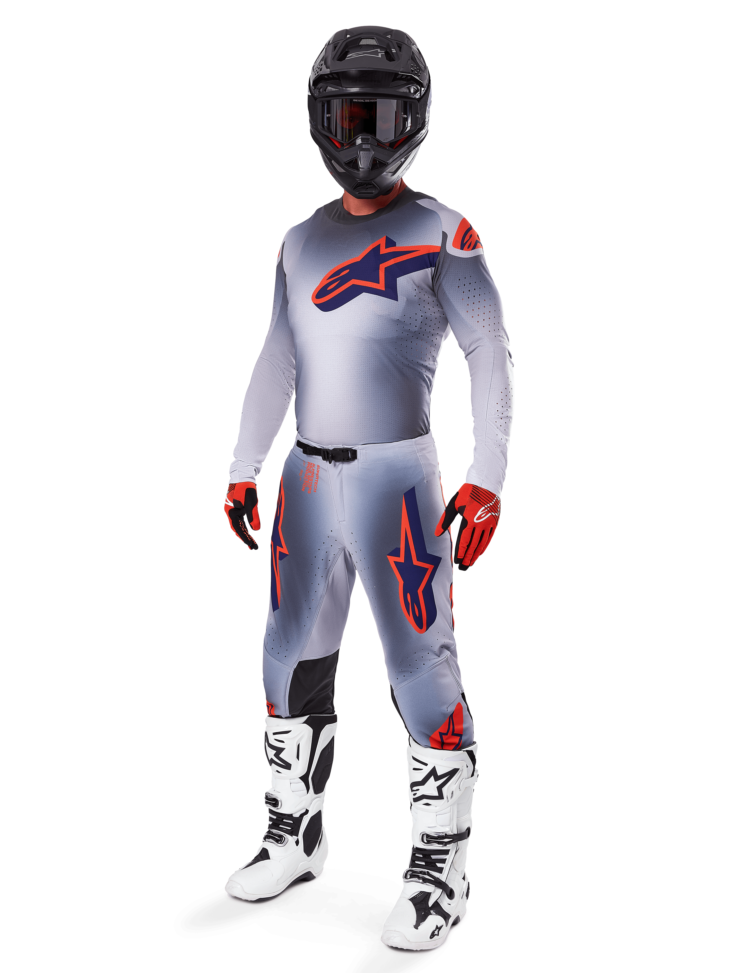 Alpinestars 2025 Supertech Lipan Gear Set, motorcross race-uitrusting, grijs met fluo oranje en marineblauwe ster-graphics, gedragen met een zwarte helm, rood-zwarte handschoenen en wit-zwarte laarzen, complete professionele off-road outfit met geventileerd ontwerp