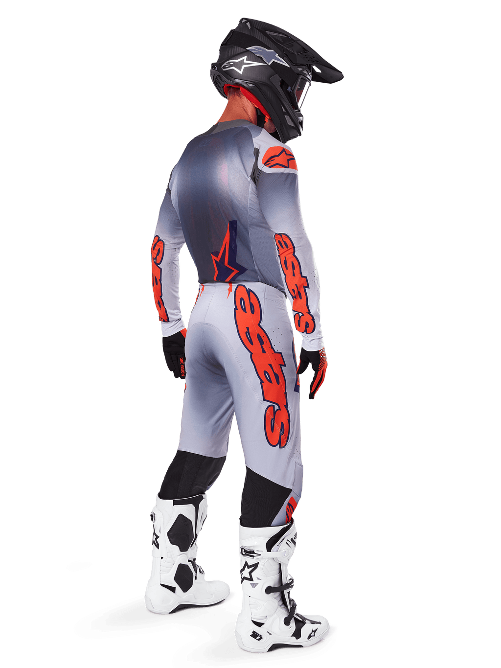 Alpinestars 2025 Supertech Lipan Gear Set, motocrossrijder van achteren gezien, grijs en oranje fluo jersey met bijpassende broek, opvallende oranje branding op de mouwen en pijpen, zwarte helm, wit-zwarte motorcrosslaarzen, professionele off-road race-outfit