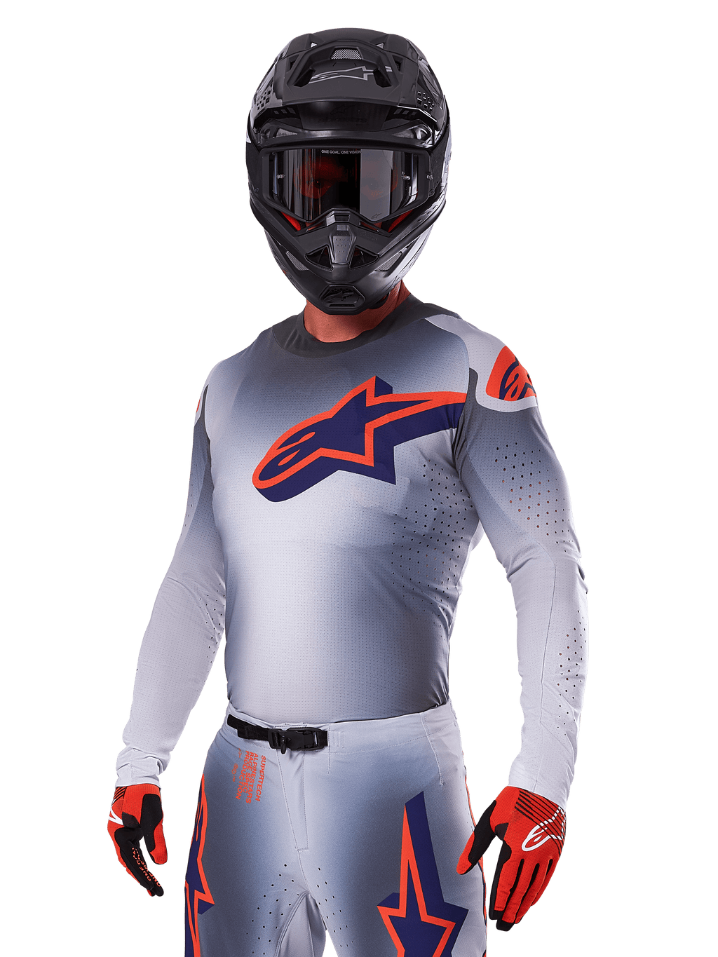 Motorcrosser in Alpinestars 2025 Supertech Lipan Gear Set, grijze jersey en broek met marineblauwe en oranje accenten, matzwarte helm met crossbril en rood-zwarte handschoenen, atletische prestatiekleding voor off-road racen