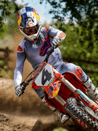 Motocrossrijder in actie op een zandcircuit, gekleed in de Alpinestars 2025 Supertech Lipan Jersey in Gray Orange Fluo, bijpassende grijze broek met oranje accenten, witte laarzen en een Red Bull-helm, terwijl hij een bocht neemt op een oranje crossmotor met opspattend zand, professionele off-road race-uitrusting.