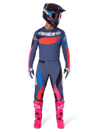 Alpinestars 2025 Techstar Dreem Gear Set, motorcrossrijder in volledige race-uitrusting, grijsblauwe jersey en broek met felle roze, oranje en cyaanblauwe accenten, groot 'astars' logo op de borst, felroze laarzen, zwarte helm met crossbril, gecoördineerde outfit voor professionele motorcross