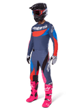 Alpinestars 2025 Techstar Dreem motorcrossuitrusting, complete off-road race-outfit met een grijs en blauw jersey met rode accenten, bijpassende broek met roze accenten, zwarte helm, felroze laarzen en wit-zwarte handschoenen