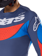 Close-up van de Alpinestars 2025 Techstar Dreem Jersey, marineblauw met felblauwe en oranje accenten, witte Alpinestars-logo's op de borst en schouder, voorzien van lasergesneden perforaties voor ventilatie