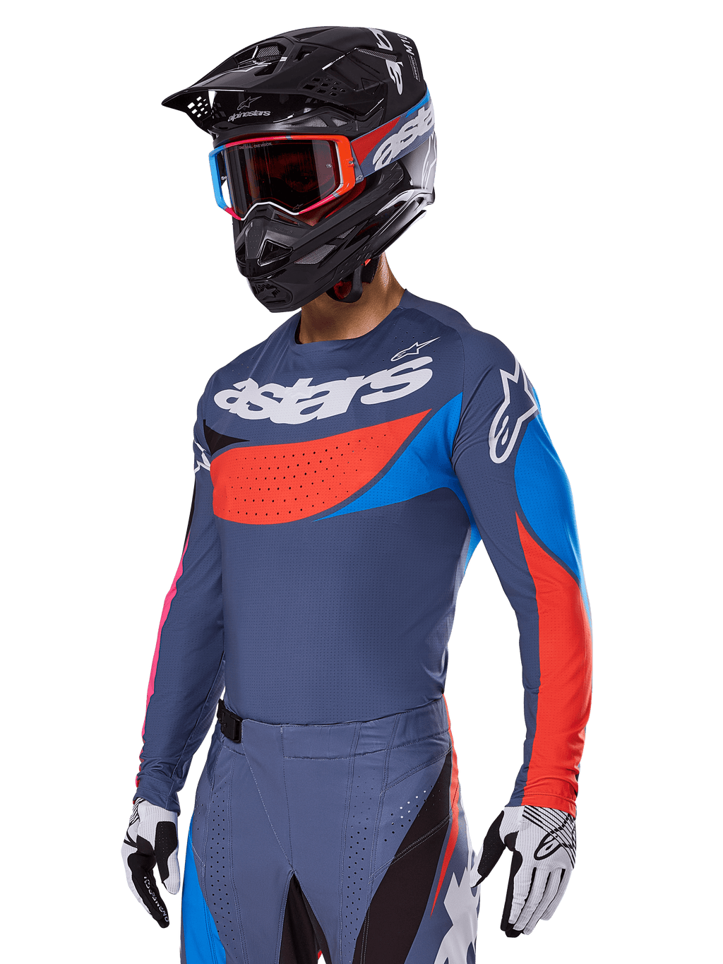 Alpinestars 2025 Techstar Dreem gear set, motorcrosser in leigrijze jersey en broek met opvallende rode en blauwe graphics, voorzien van 'astars'-branding op de borst, gecombineerd met een zwarte helm, crossbril met rood montuur en witte racehandschoenen
