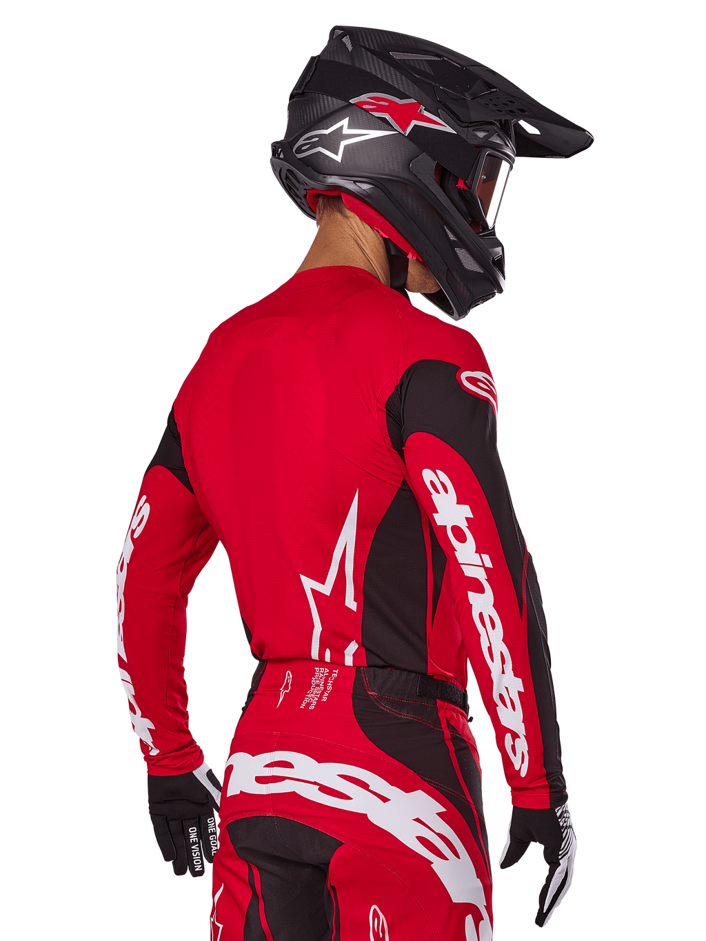 Motorcrosser van achteren gezien in Alpinestars 2025 Techstar Dreem gearset, rood en zwart jersey met witte merknaam op de mouwen, bijpassende rood-zwarte broek met opvallend wit logo op het zitvlak, zwarte carbon helm met rode accenten, zwart-witte handschoenen, professionele off-road outfit.