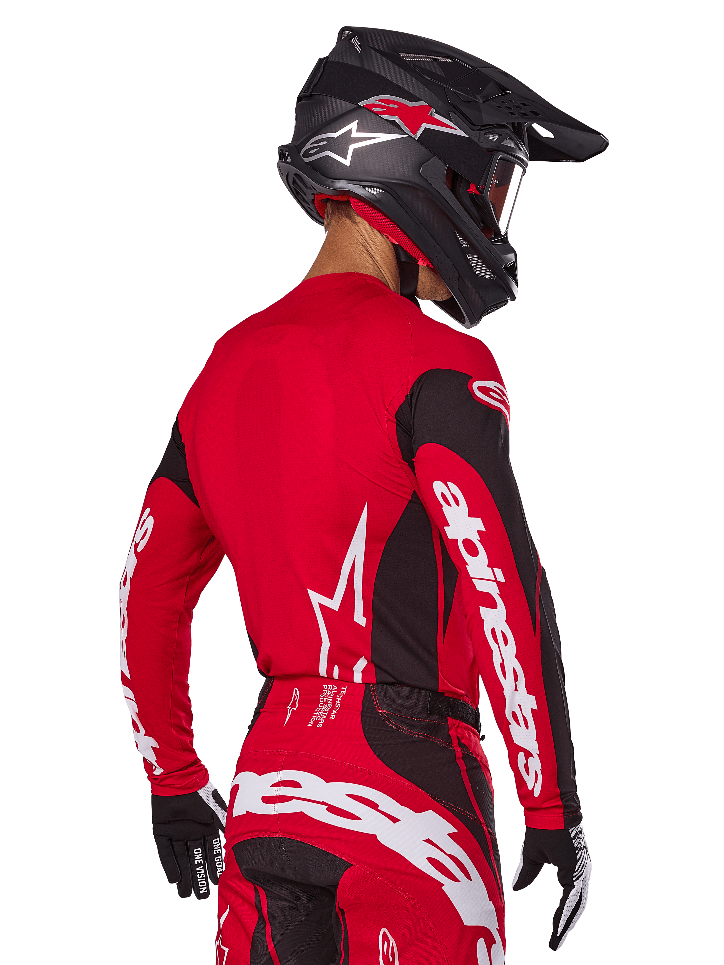 Motorcrosser van achteren gezien in Alpinestars 2025 Techstar Dreem gearset, rood en zwart jersey met witte merknaam op de mouwen, bijpassende rood-zwarte broek met opvallend wit logo op het zitvlak, zwarte carbon helm met rode accenten, zwart-witte handschoenen, professionele off-road outfit.