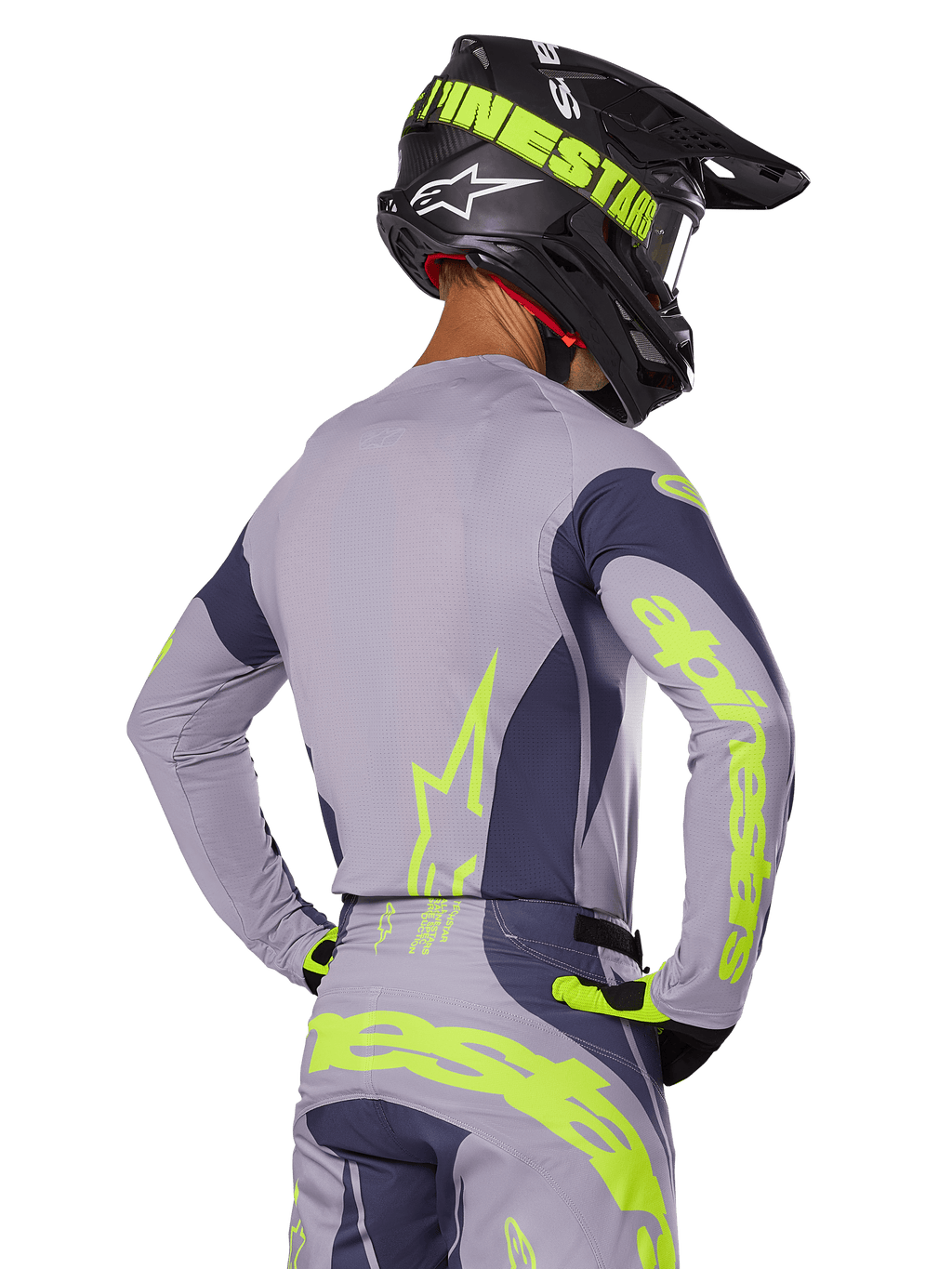 Motorcrosser van achteren in Alpinestars 2025 Techstar Dreem Gear Set, grijze jersey en broek met opvallende neongeel-groene branding, bijpassende zwarte helm met neon graphics, professionele motorcross outfit