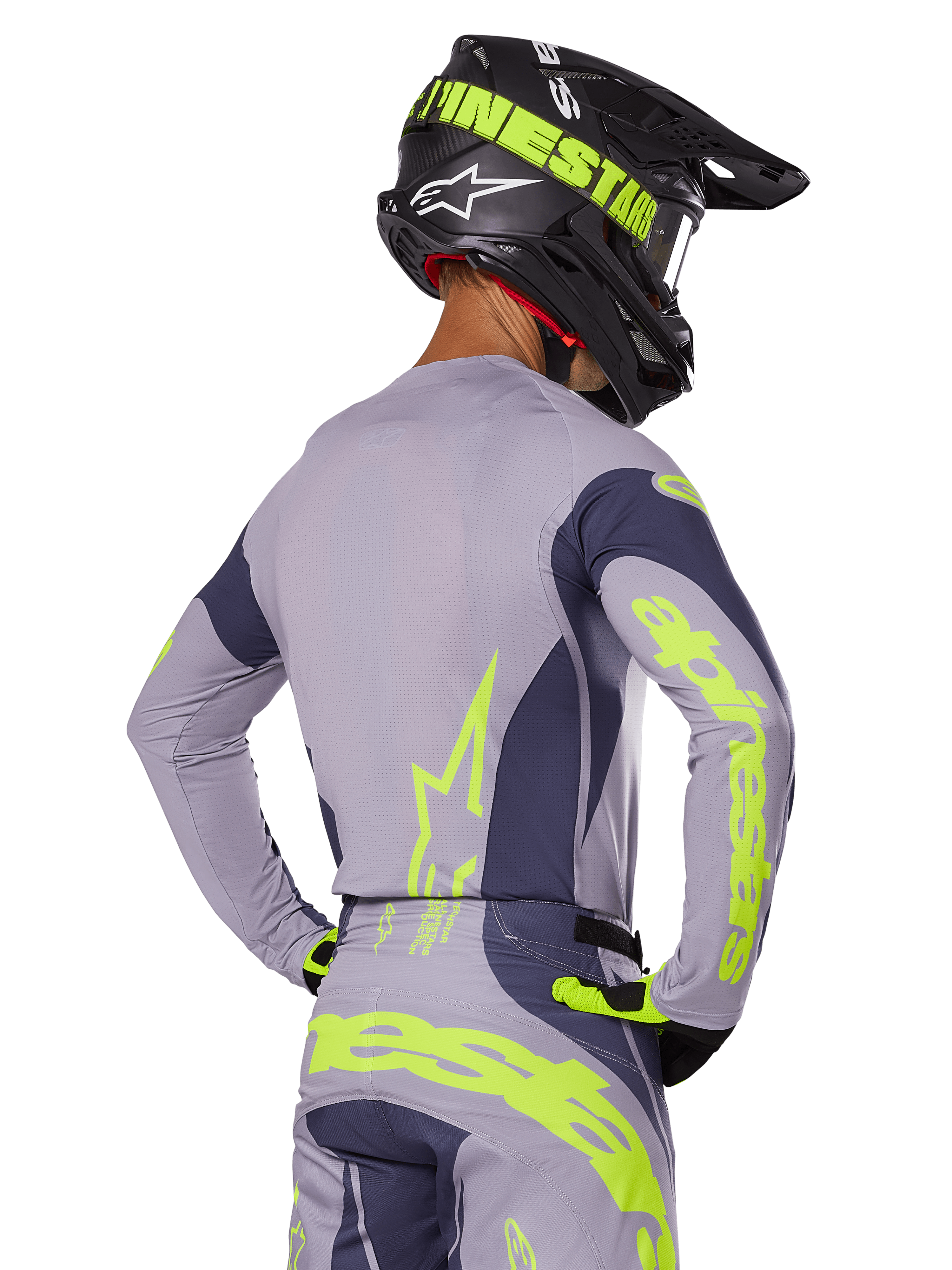 Motorcrosser van achteren in Alpinestars 2025 Techstar Dreem Gear Set, grijze jersey en broek met opvallende neongeel-groene branding, bijpassende zwarte helm met neon graphics, professionele motorcross outfit