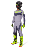 Alpinestars 2025 Techstar Dreem Gear Set, motorcrosser in volledige race-outfit, grijs shirt en broek met donkergrijze patronen en neon geelgroene accenten, bijpassende zwarte helm, neon geelgroene handschoenen en laarzen, hoogwaardige off-road uitrusting