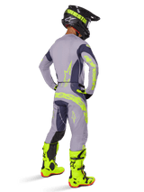 Alpinestars 2025 Techstar Dreem Jersey, motorcross shirt, grijs en donkergrijs, gedragen met bijpassende broek en felle neongele laarzen, achteraanzicht met neongele branding en atletische pasvorm voor off-road racen