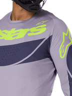 Alpinestars 2025 Techstar Dreem Jersey, motorcross jersey, grijs en marineblauw met fel limoengroen logo, close-up van rijder met zwarte helm, voorzien van laser-gesneden perforaties voor ventilatie