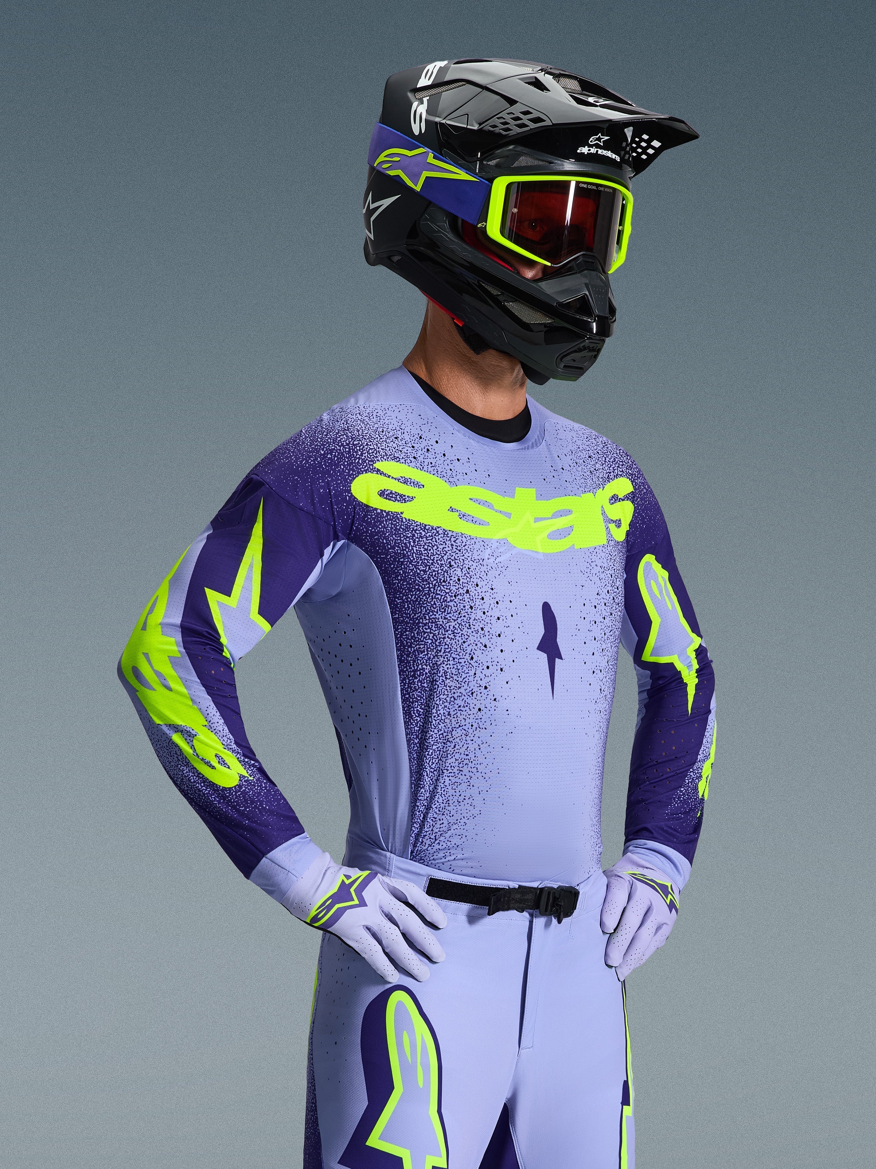 Alpinestars 2026 Supertech Scenz Gear Set, Motocross rider wearing lavender and dark purple racing gear with neon yellow accents, matching helmet and goggles, athletic pro-fit jersey and pants with bold branding