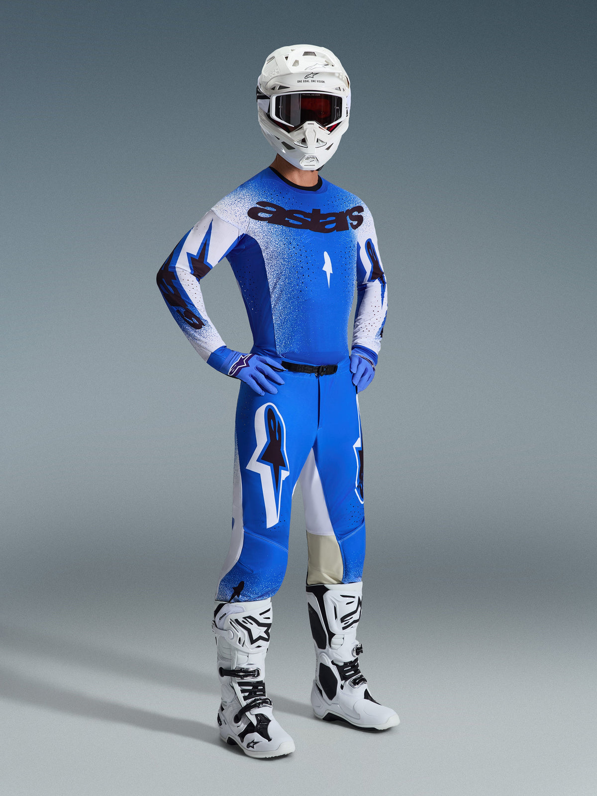 Motocross rider wearing the Alpinestars 2026 Supertech Scenz Gear Set in Ucla Blue and White, featuring a pro-level jersey with 'astars' branding, matching performance pants, white helmet, dark goggles, and white and black off-road boots.