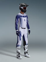Alpinestars motorcrosser in complete professionele race-uitrusting, 2026 Supertech Scenz Jersey in lichtgrijs en donkerblauw, bijpassende crossbroek met ster-graphics, zwarte helm met rode crossbril, witte en zwarte performance-laarzen en gecoördineerde blauwe en witte handschoenen voor off-road racing.