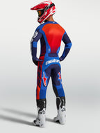 Alpinestars Racer Hunt jersey, heren-motocrossuitrusting, blauw en rood, vochtafvoerend polyfabric, achterzijde van model met volledige off-road uitrusting en witte laarzen
