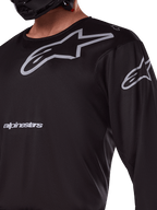 Alpinestars 2025 Racer Graphite Jersey, Black and Gray, close-up of rider wearing motocross jersey, featuring grey Alpinestars branding and A-star logos, technical poly-fabric material for off-road riding
