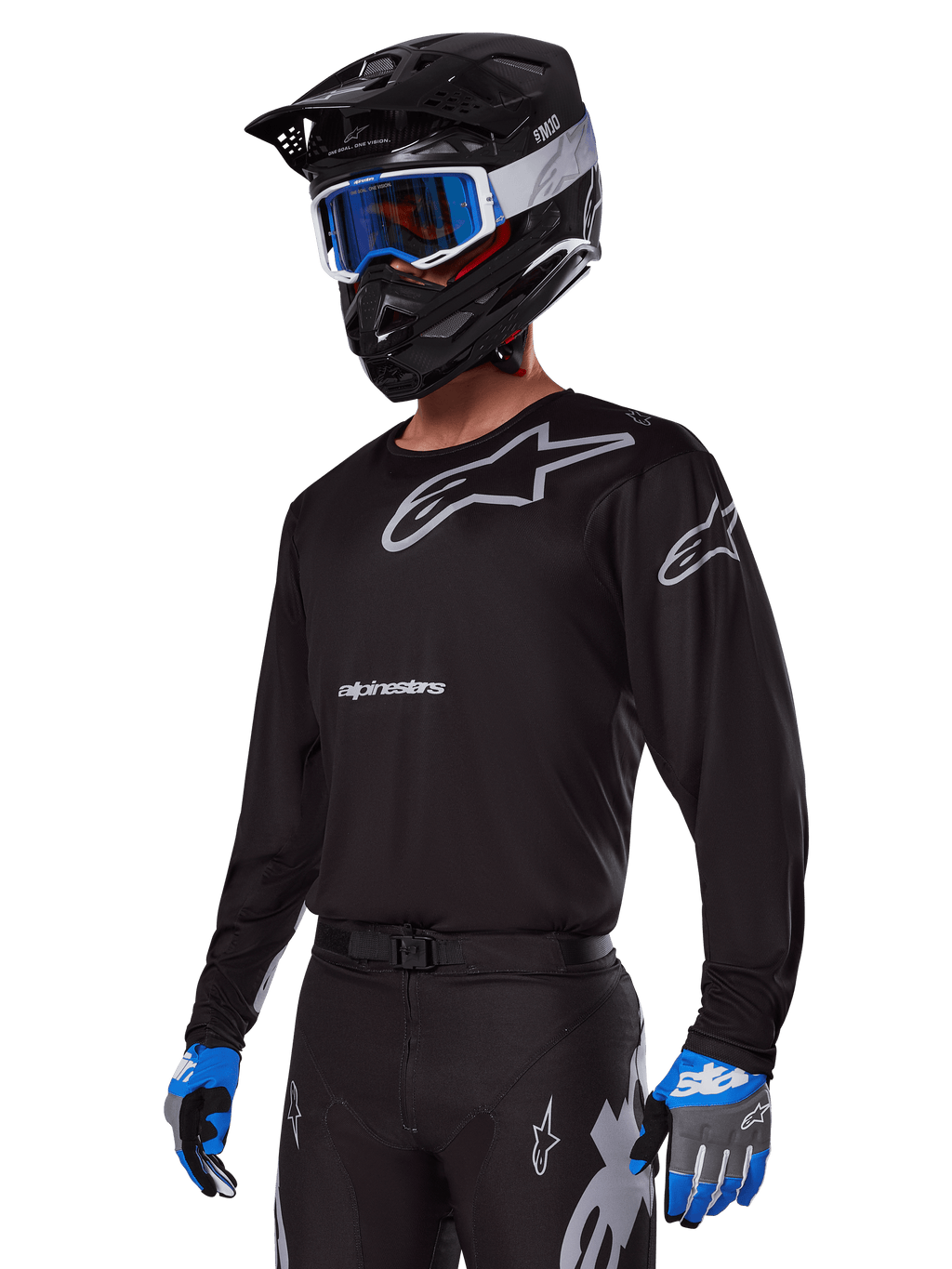 Motorcrosser in Alpinestars 2025 Racer Graphite Gear Set, zwart shirt met grijze Alpinestars-logo's, bijpassende zwarte broek met grijze accenten, zwarte helm met blauwe en witte bril, blauwe en grijze handschoenen, strakke technische outfit voor off-road racen