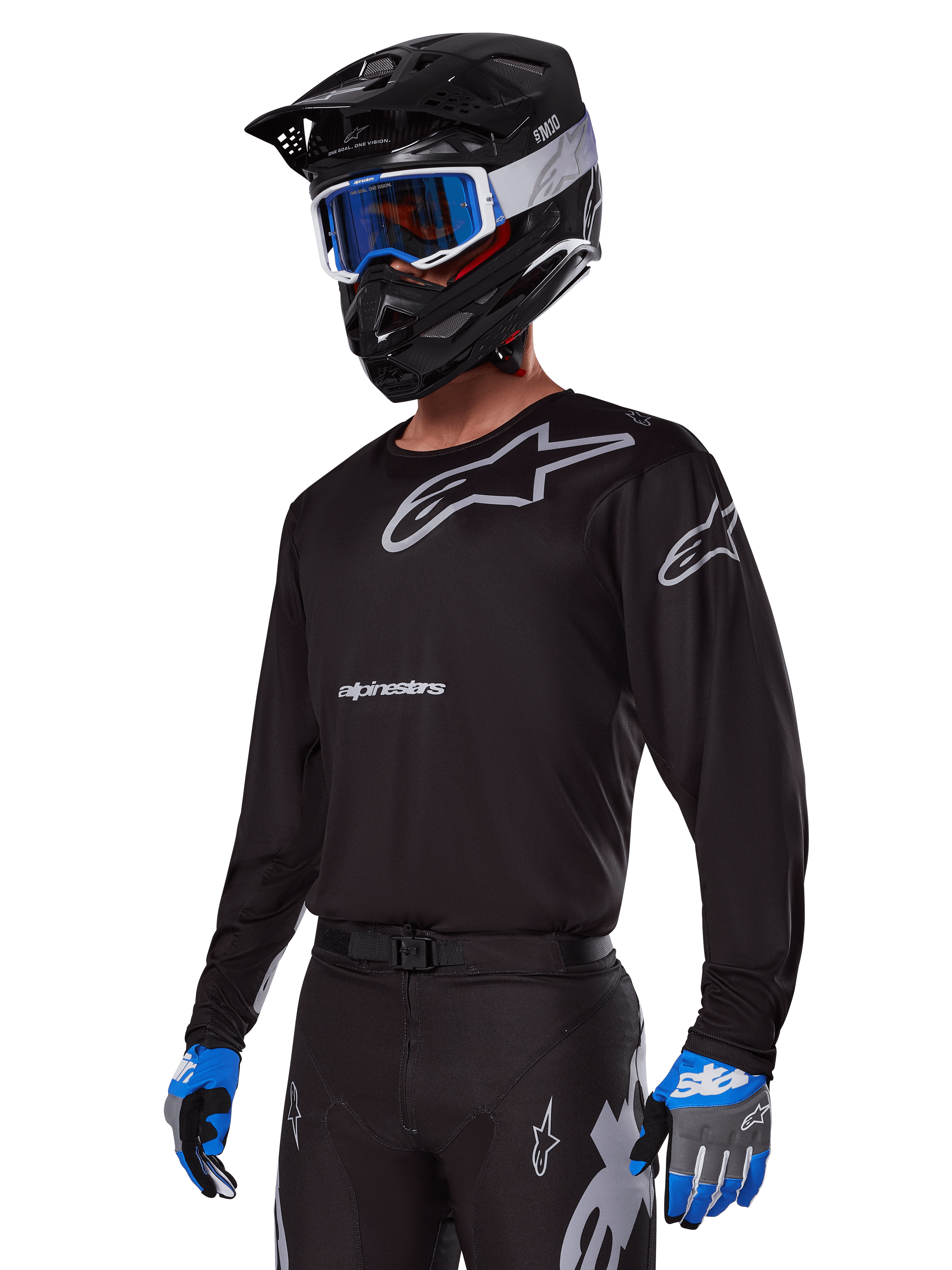 Motorcrosser in Alpinestars 2025 Racer Graphite Gear Set, zwart shirt met grijze Alpinestars-logo's, bijpassende zwarte broek met grijze accenten, zwarte helm met blauwe en witte bril, blauwe en grijze handschoenen, strakke technische outfit voor off-road racen