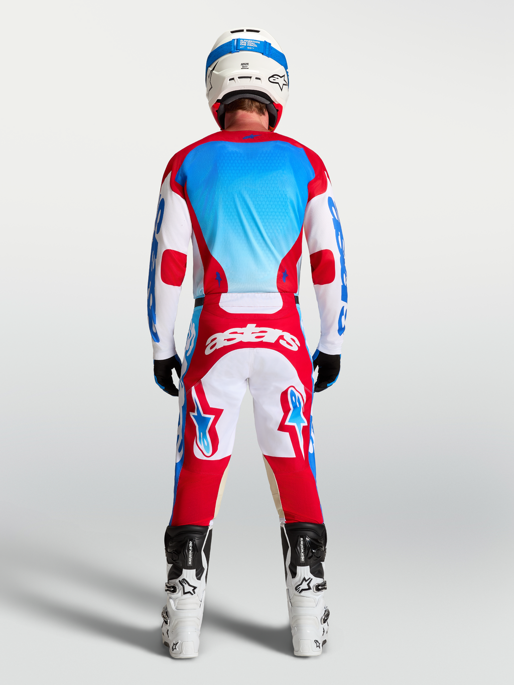 Alpinestars Racer Hunt broek en gear set, rood, wit en blauw, achteraanzicht op model in motocrossuitrusting.