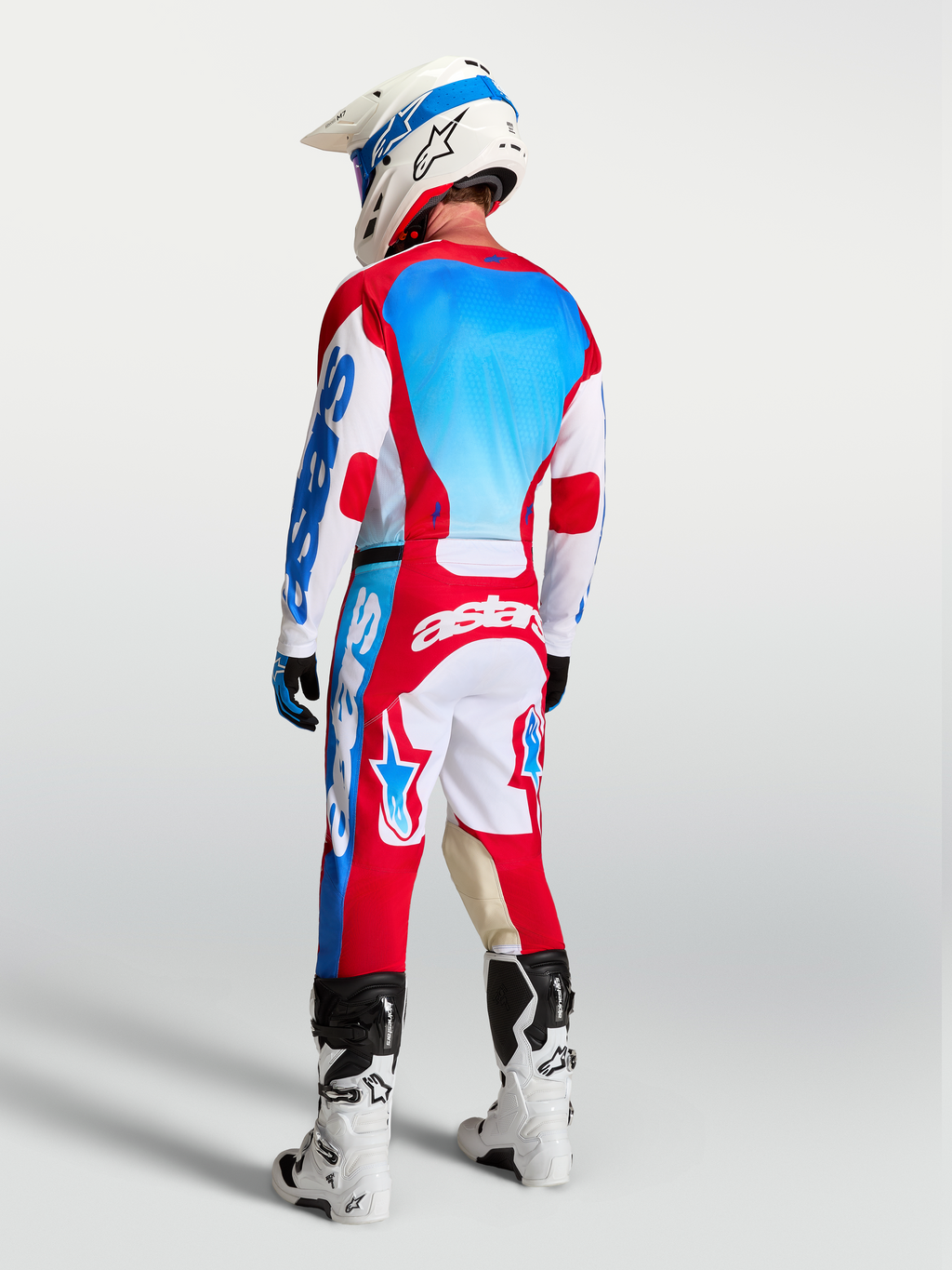 Alpinestars Racer Hunt broek en gear set, heren motorcrossuitrusting, rood, wit en UCLA blauw, achteraanzicht op rijder.