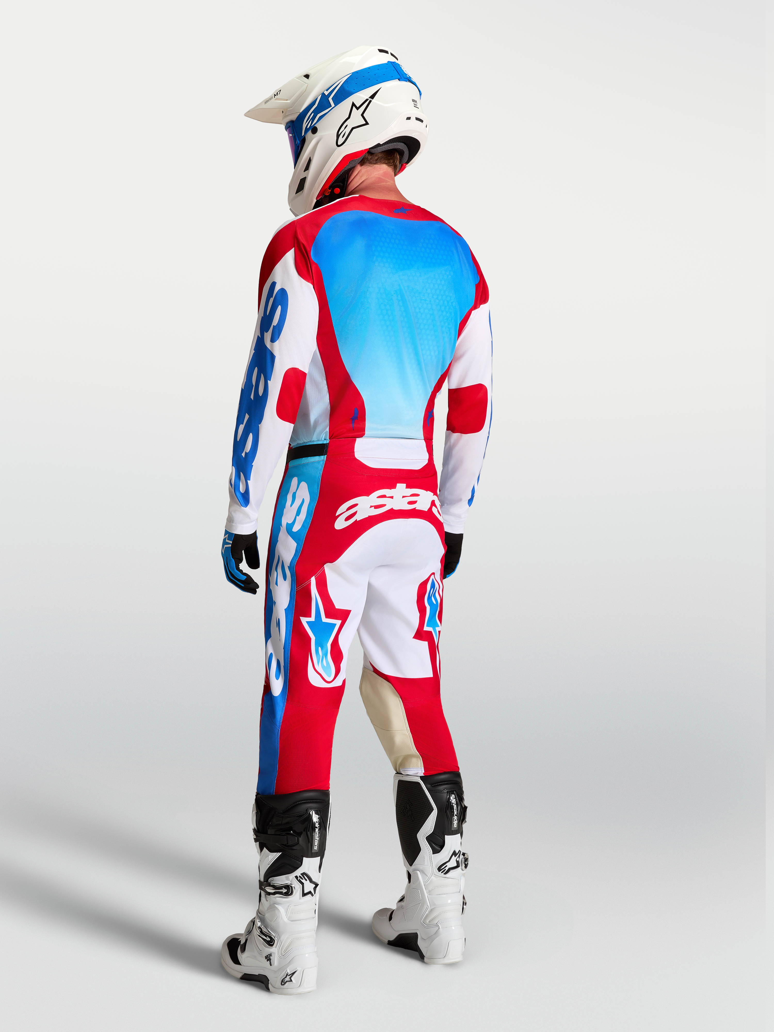 Alpinestars Racer Hunt broek en gear set, heren motorcrossuitrusting, rood, wit en UCLA blauw, achteraanzicht op rijder.