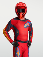 Alpinestars Racer Hunt jersey, rood en grijs motocross-shirt met mesh-panelen, gedragen door een model met bijpassende helm en MX-uitrusting.