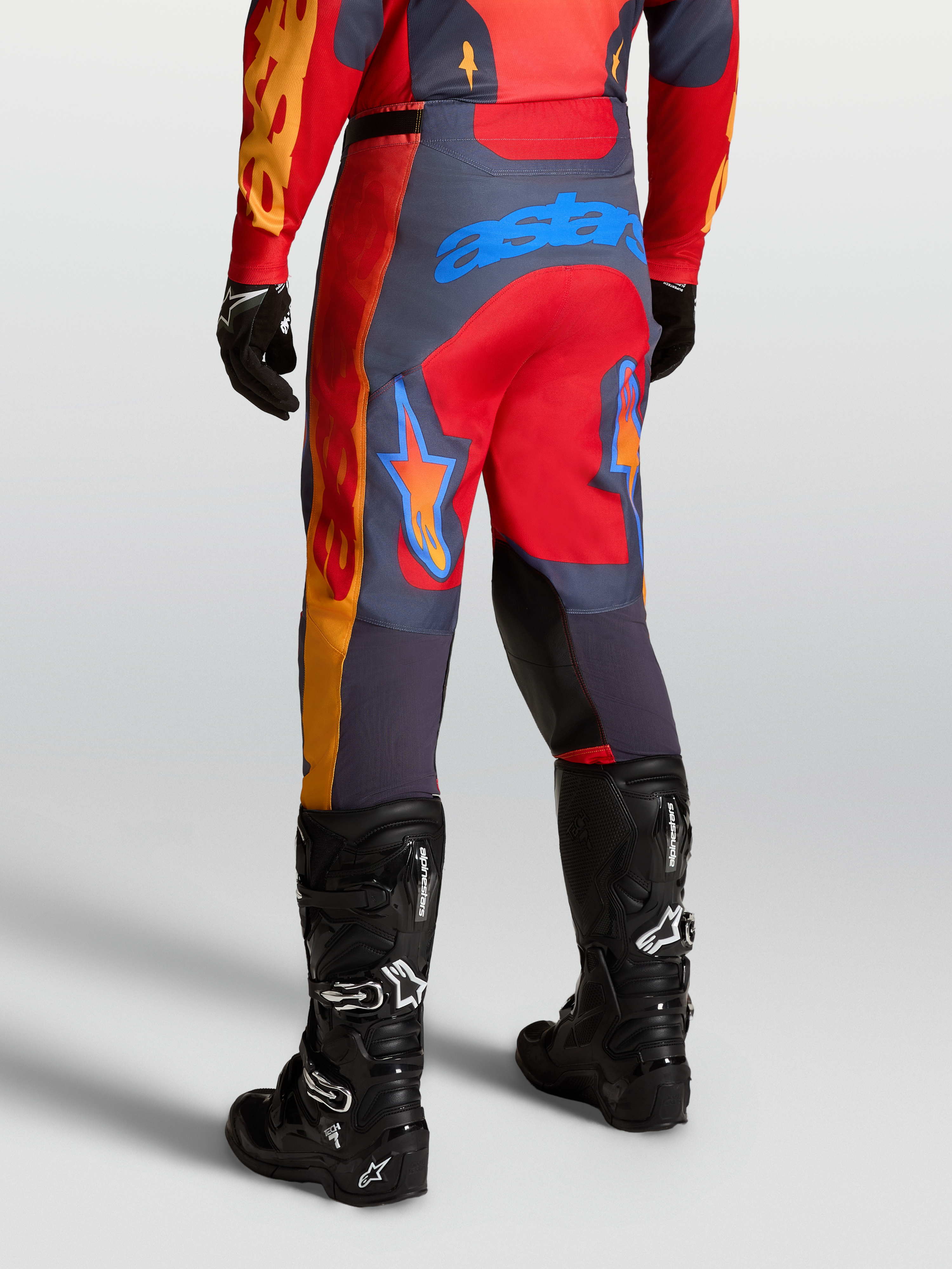 Alpinestars Racer Hunt Pants, performance motocross racing pants in Fire Red and Graystone, shown from the rear in a sport riding position.
