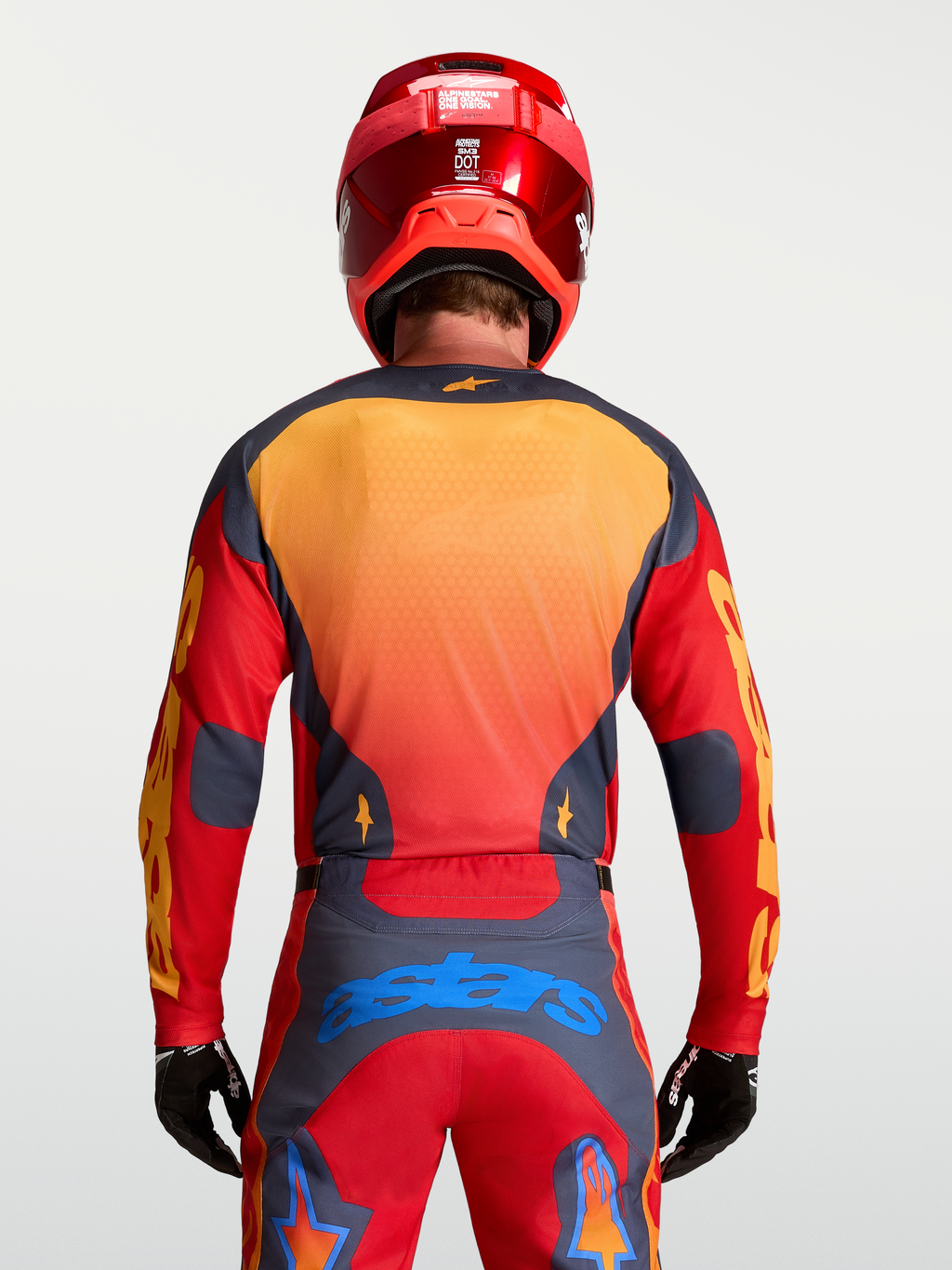 Alpinestars Racer Hunt jersey voor heren, motorcross kleding in rood en grijs, achteraanzicht op model met helm.
