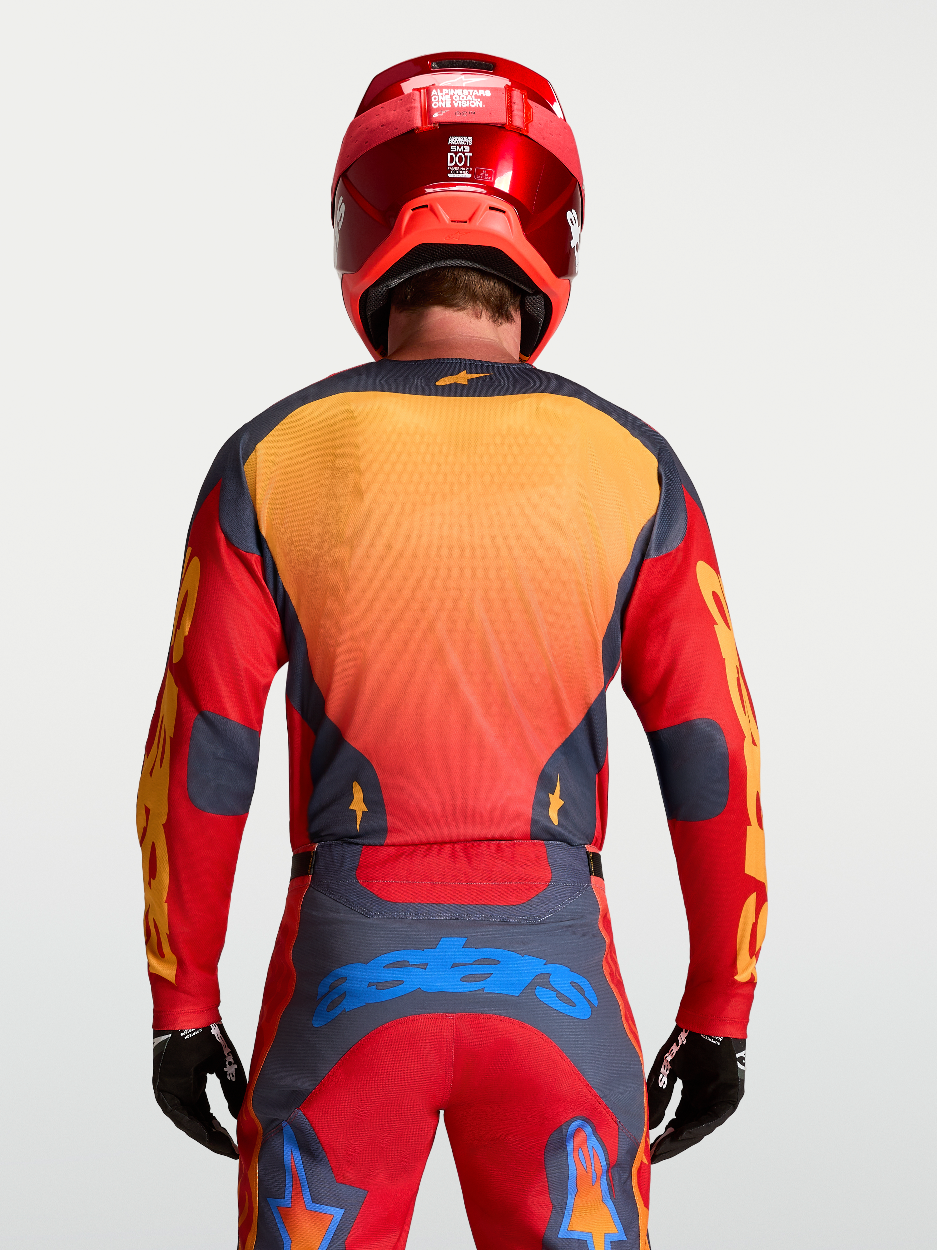 Alpinestars Racer Hunt jersey voor heren, motorcross kleding in rood en grijs, achteraanzicht op model met helm.